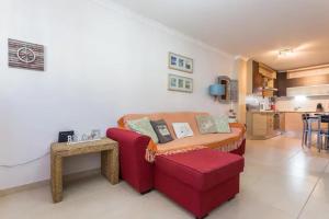 ein Wohnzimmer mit einem roten Sofa und einem Tisch in der Unterkunft Apartamento sobre a praia in Olhos de Água
