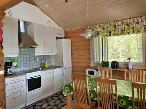 a kitchen with white cabinets and a table and chairs at Lappalaisen lomamökit Norpparanta in Puumala