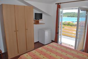 a bedroom with a bed and a sliding door with a balcony at Apartmani Ivan in Kaprije