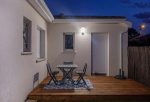 une terrasse couverte avec 2 chaises et une table. dans l'établissement Studio Nathalie et Sebastien, à La Brède