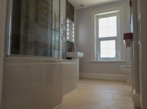a bathroom with a tub and a sink and a window at Carriers Cottage, Isle of Wight in Shanklin