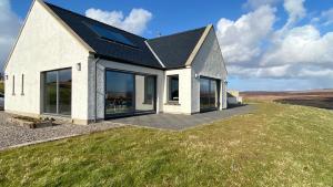 a white house on top of a grassy field at Captain’s Rest in Dunvegan