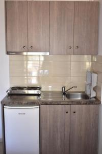 een keuken met houten kasten, een wastafel en een vaatwasser bij Michalis Place Apartments in Vasiliki