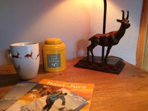 a table with a figurine of a deer and a mug at La Marténie in Mijoux