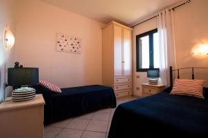 a hotel room with two beds and a television at Residence SardegnaSummer Li Cuppulati in San Teodoro