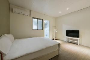 ein weißes Schlafzimmer mit einem Bett und einem TV in der Unterkunft 逢甲All Night龍 in Taichung