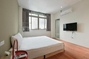 ein Schlafzimmer mit einem großen Bett und einem TV in der Unterkunft 逢甲All Night龍 in Taichung