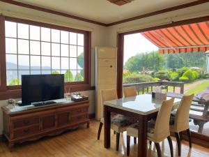 ein Esszimmer mit einem TV und einem Tisch mit Stühlen in der Unterkunft Namhea German Village Beethoven House in Namhae