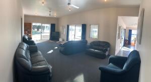 a living room with couches and chairs and a television at Spires Barn Lodge in Christchurch