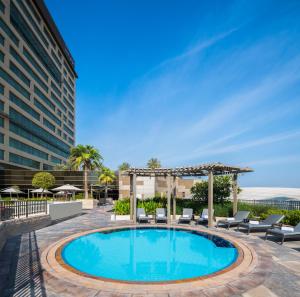 een zwembad in een hotel met stoelen en een prieel bij Swissôtel Living Al Ghurair in Dubai