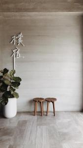 due sgabelli in legno in una stanza con una pianta di 樸宿民宿 非親子民宿 僅接待12歲以上成人 a Guanshan