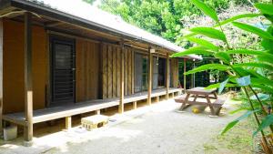 a wooden house with a bench and a table at Mannaya -SEVEN Hotels and Resorts- in Motobu