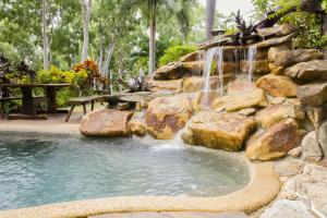 a waterfall in a pool with a stone wall at Milkwood Lodge in Cooktown