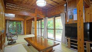 a living room with a table and a tv at Mannaya -SEVEN Hotels and Resorts- in Motobu