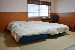a large bed in a bedroom with a window at Annex Aburaya in Iiyama