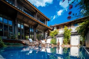 a house with a pool in front of a building at 丽江无尔雪山下泳池花园民宿 in Lijiang