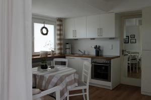 a kitchen with a table and a kitchen with white cabinets at Seeblick in Westensee