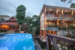 a villa with a swimming pool in front of a house at Merak Village by Prasi in Ubud