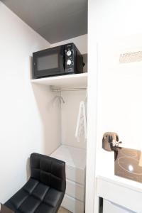 a black stool in a bathroom with a tv on a shelf at Hill Side Terrace Hiroo Shibuya 201 in Tokyo