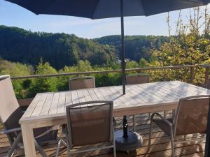 einem Holztisch mit Stühlen und einem Sonnenschirm auf einer Terrasse in der Unterkunft Chalet Bonne Humeur in Houffalize