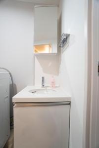 La salle de bains blanche est pourvue d'un lavabo et d'un miroir. dans l'établissement Hill Side Terrace Hiroo Shibuya 203, à Tokyo