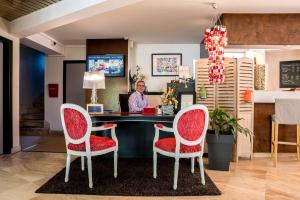 a man sitting at a desk with two red chairs at Carnac Lodge Hotel & Spa in Plouharnel