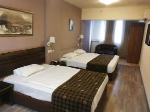 a hotel room with two beds and a chair at Astoria Galilee Hotel in Tiberias