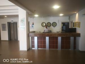 un homme debout à un comptoir dans une pièce avec des horloges sur le mur dans l'établissement Astoria Galilee Hotel, à Tibériade