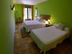 two beds in a room with green walls at Hotel Rural Los Molinillos in El Arenal