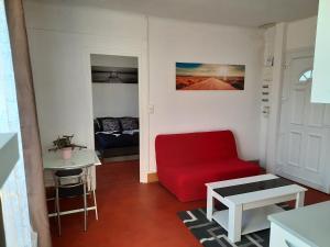 a living room with a red chair and a table at Le studio d Olivia in Avallon