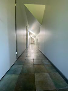 un couloir vide avec des murs blancs et du carrelage dans l'établissement Guest House Pilsētnieki, à Slampe