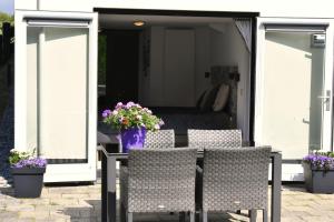 un patio con 2 sillas y una mesa con flores en BzonderB Callantsoog, en Callantsoog