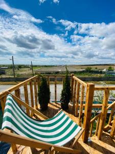a wooden rocking chair sitting on a deck at Ca acasă Corbu in Corbu