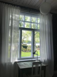 een raam met witte gordijnen en een bureau ervoor bij Willa Strand in Kristiinankaupunki