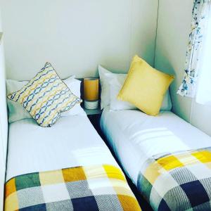 two beds sitting next to each other in a room at 12 Borwick Lakes by Waterside Holiday Lodges in Carnforth
