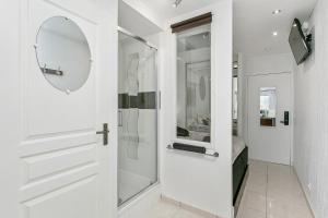 a white bathroom with a shower and a glass door at L'After Port Nature in Cap d'Agde