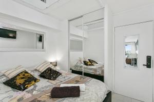 Habitación blanca con cama y espejo en L'After Port Nature, en Cap d'Agde