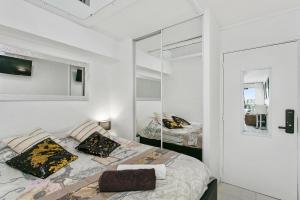 a white bedroom with a bed and a mirror at L'After Port Nature in Cap d'Agde