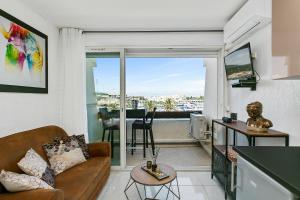 a living room with a couch and a balcony with a view at L'After Port Nature in Cap d'Agde