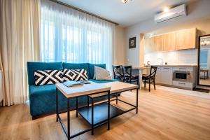 a living room with a blue couch and a table at Apartamenty Sun & Snow Bukowa Dolina in Krynica Zdrój