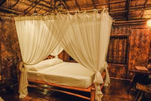 um quarto com uma cama de dossel e cortinas em Flower Island Resort em Taytay