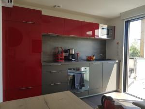eine Küche mit roten Schränken und einer roten Wand in der Unterkunft Studio de Lokentaz in Saint-Gildas-de-Rhuys