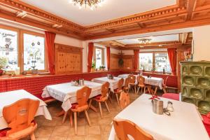 ein Restaurant mit Tischen, Stühlen und Fenstern in der Unterkunft Pension Christophorus in Kaprun