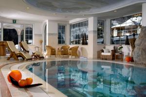basen w hotelu z krzesłami i stołami w obiekcie Kristiania Pure Nature Hotel & Spa w mieście Cogolo