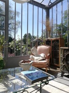 a conservatory with a chair and a glass table at La Pluie de Roses in Giverny