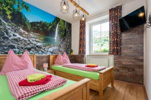Dos camas en una habitación con un mural de cascada. en Freelife Guesthouse, en Grossreifling