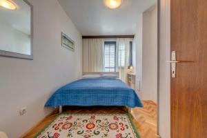 a small bedroom with a blue bed and a rug at Apartments Marjan in Split