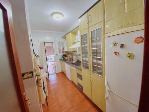een keuken met gele kasten en een witte koelkast bij Apartamento de 3 habitaciones, zona muy tranquila a unos minutos de la playa in Mazagón