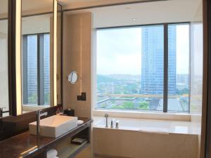 een badkamer met een bad en een wastafel en een groot raam bij Hyatt Regency Fuzhou Cangshan in Fuzhou