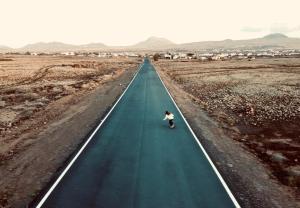a person riding a skateboard down a long road at Surfescape Fuerteventura in Lajares